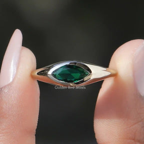 Two fingers holding the Green Marquise Cut Bezel Set Moissanite Ring