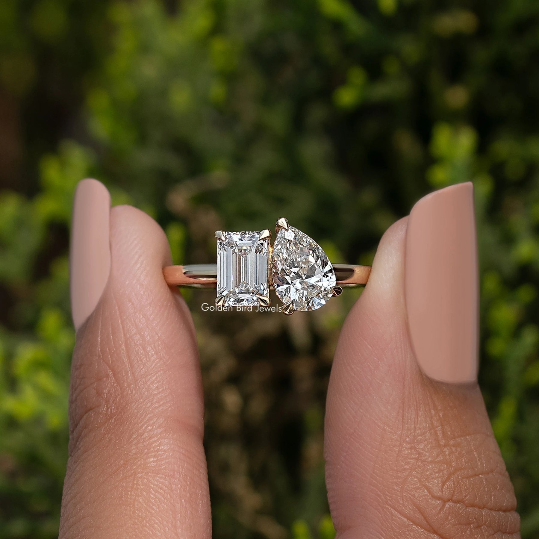 Emerald and Pear Lab Diamond Toi Et Moi Ring Held Between Fingers