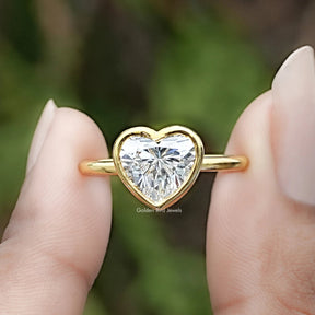 Heart Shaped Lab Diamond Bezel Set Ring Between Two Fingers