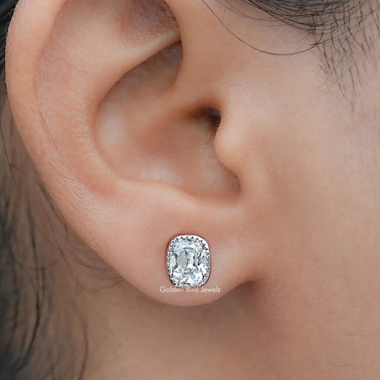 Close-up of an ear wearing a diamond stud earring with a blurred background