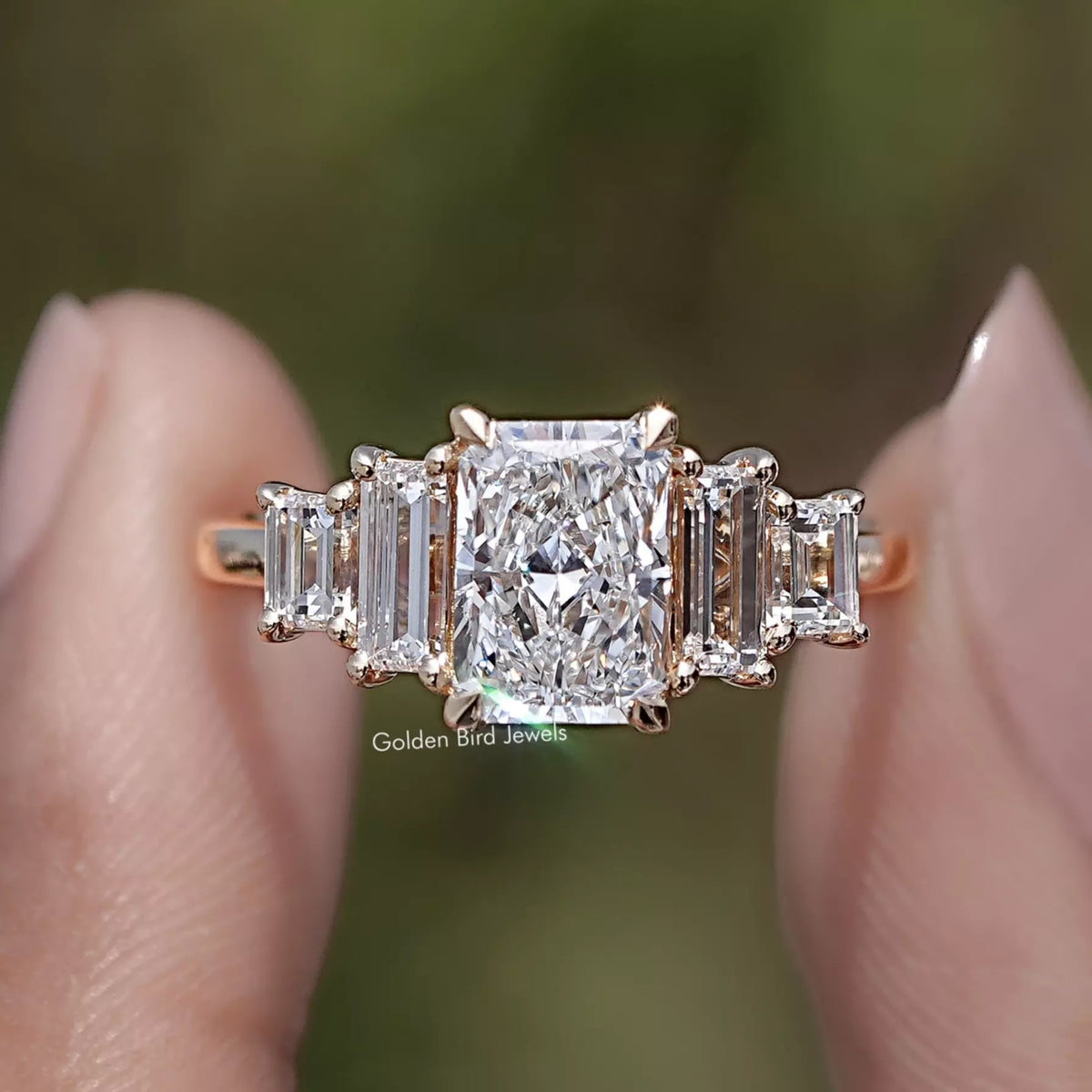 Radiant And Baguette Lab Diamond Five Stone Ring Held  Between Two Fingers