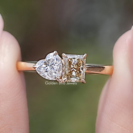 Front view of Radiant And Heart Cut Moissanite Two Stone Ring in two fingers 
