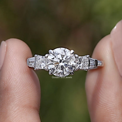 Round And Princess Diamond Five Stone Ring Between Two Fingers
