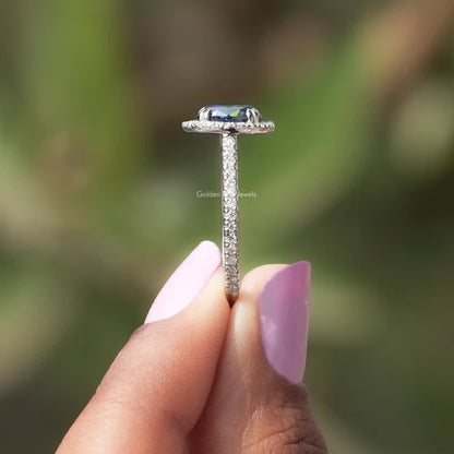 Side View of Blue Oval Cut Accent Stone Engagement Ring In two fingers